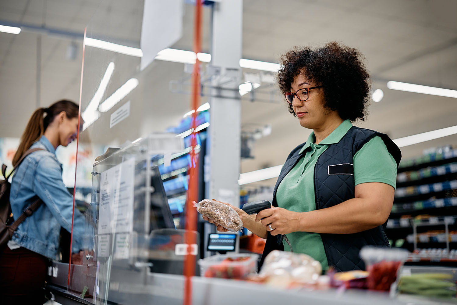 Supermarket cashier scanning customer's groceries at checkout.